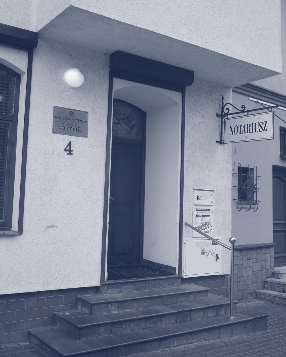 Budynek kancelarii od ulicy: wejście po schodkach, numer 4 i szyld Notariusz
